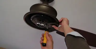 Electrician installing ceiling fan mounting bracket and fixture in Chandler, AZ