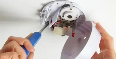 Certified technician wiring smoke detector during installation in Chandler, AZ